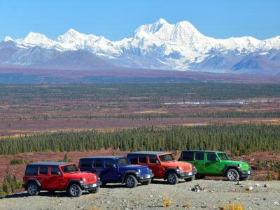 Line of jeeps in front of the eastern Alaska Range.