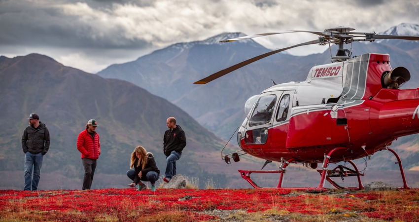 Helicopter landing on scenic ridge near Denali National Park.