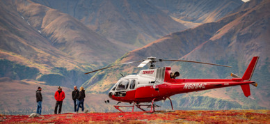 Ridge top helicopter landing among autumn colors and snow capped mountains