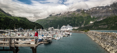 Small boat harbor in Whitter with cruise ship in the distance.