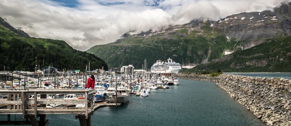 Small boat harbor in Whitter with cruise ship in the distance.