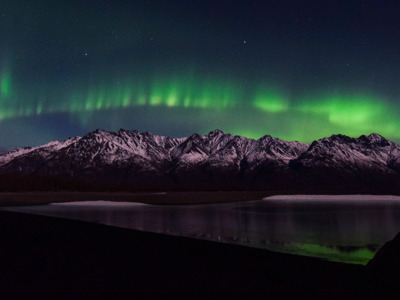 Northern lights dancing above mountain peaks near Palmer, Alaska.