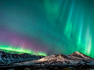 Northern lights above mountain peaks in Anchorage Alaska.