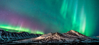 Northern lights above mountain peaks in Anchorage Alaska.