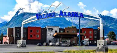 Valdez welcoming sign with Totem Hotel in background.