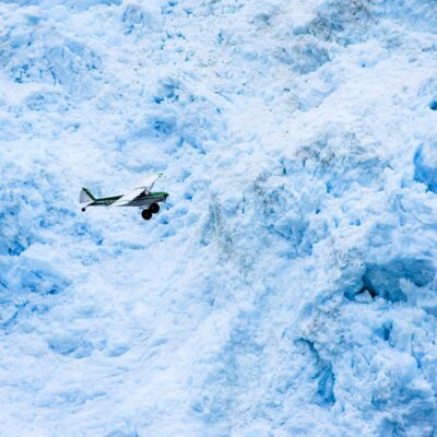Super Cub dwarfed by the face of Aialik Glacier in Kenai Fjords National Park.