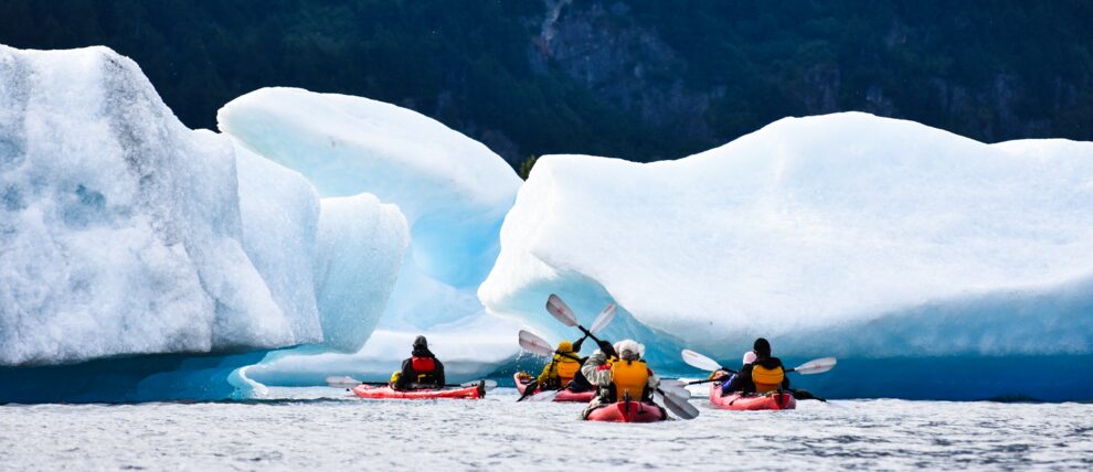 Group paddles among beached icebergs in a mountain lake near Anchorage.
