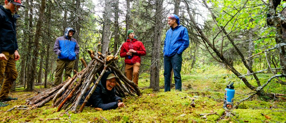 Learning shelter building skills on a survivalist hike.